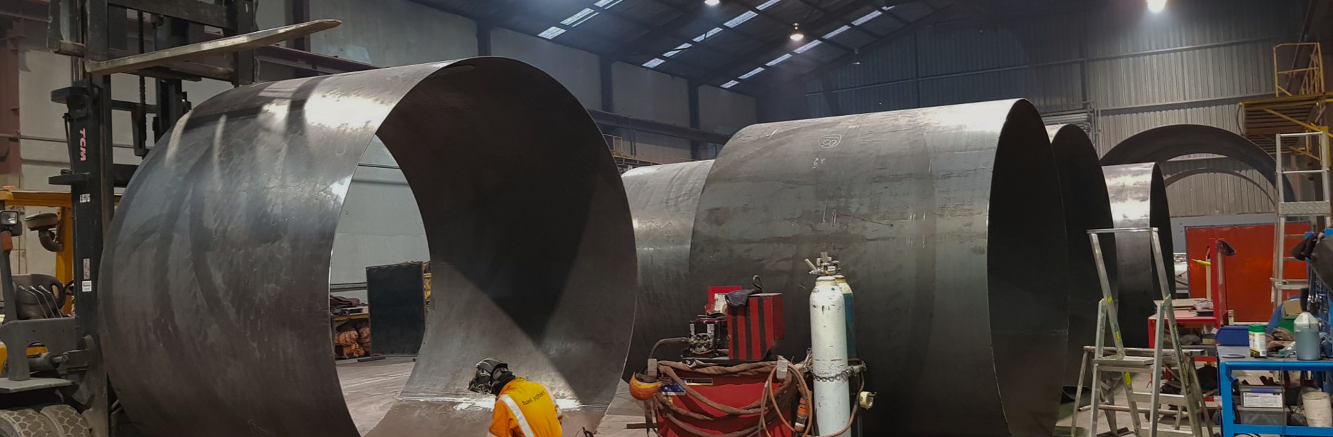 Large steel tank shells being fabricated in a workshop