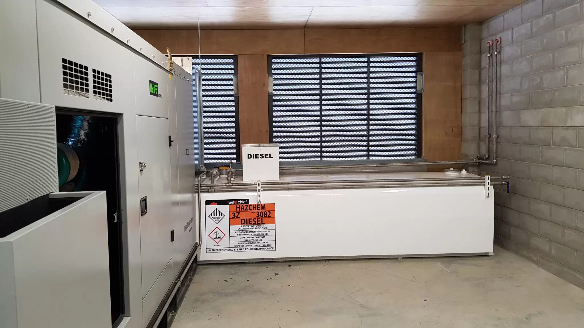 Generator room with a white diesel tank under a louvred window