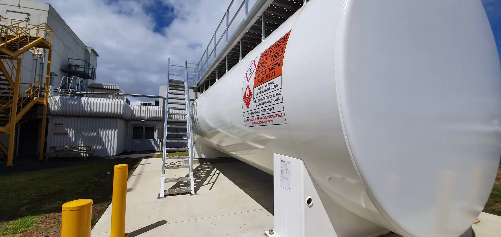 Long white tank with an access stair beside a building