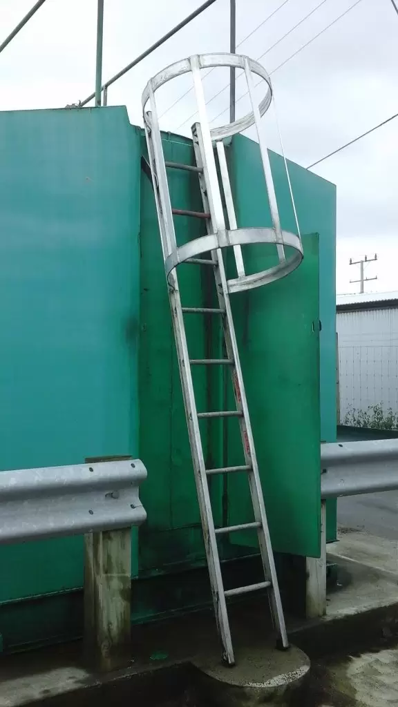 Caged access ladder on the side of a green tank