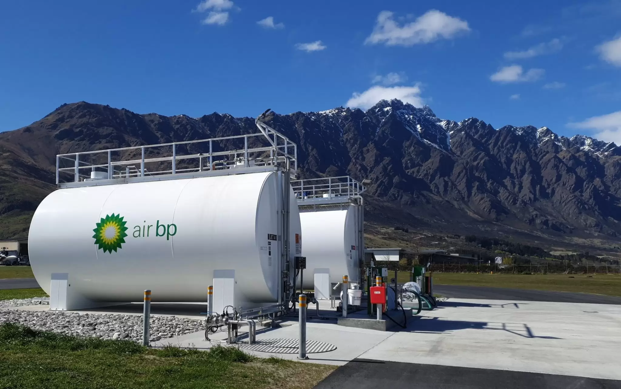 Two Air BP tanks with access platforms in front of mountains