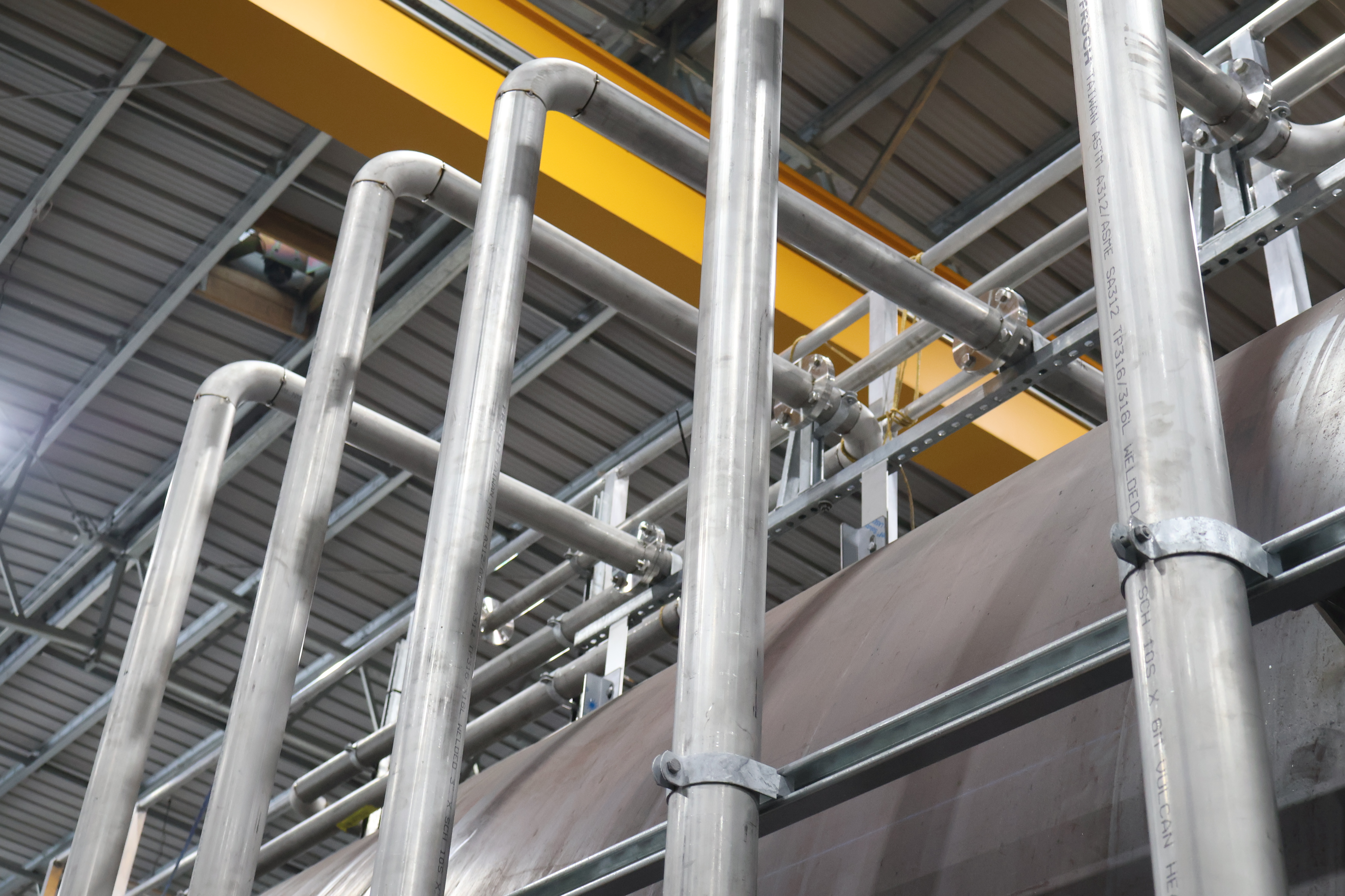 Aluminium pipework over a tank in a factory