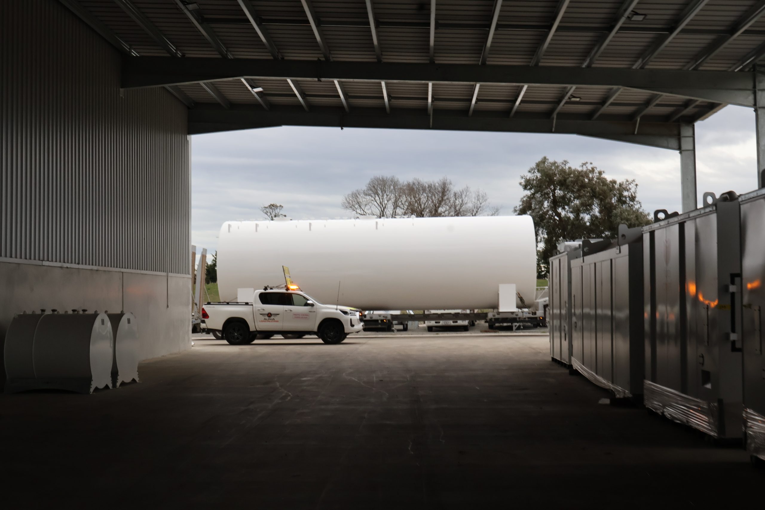 Fuel tank on a truck under a shed roof, ute and steel cabinets beside it