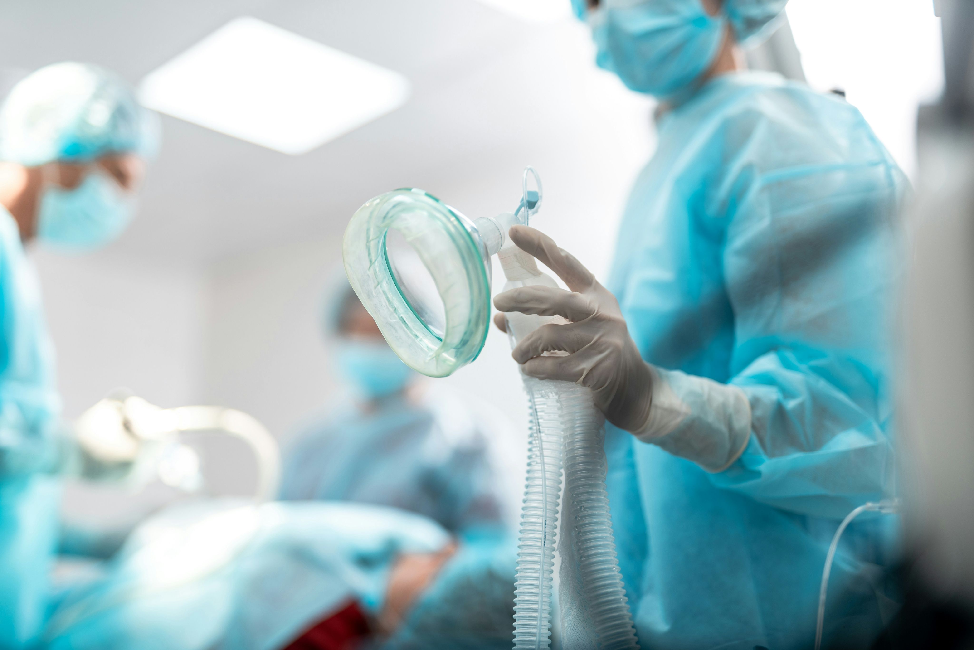 Surgical team in an operating theatre, one holding an anaesthetic mask