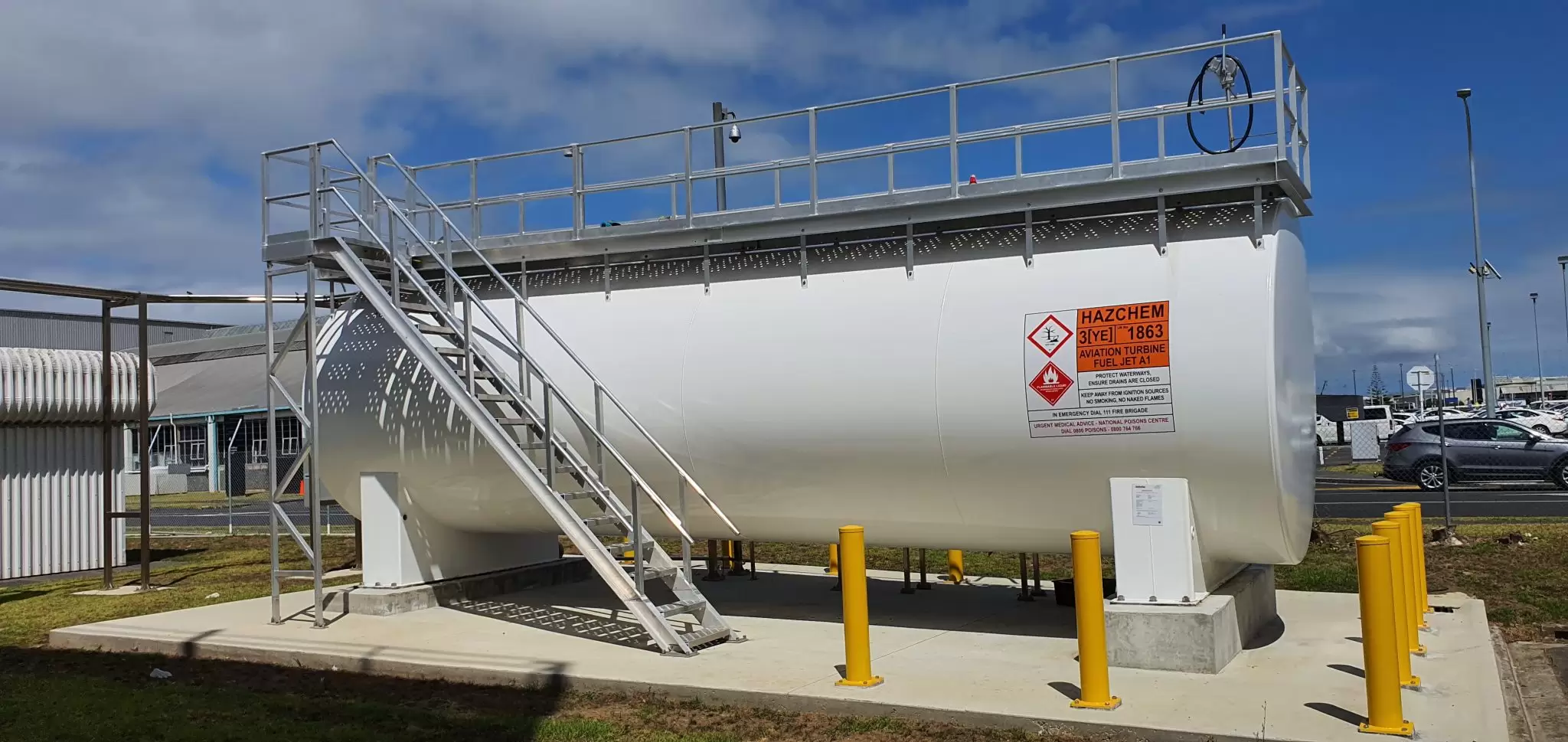 White tank with an access stair and platform behind bollards